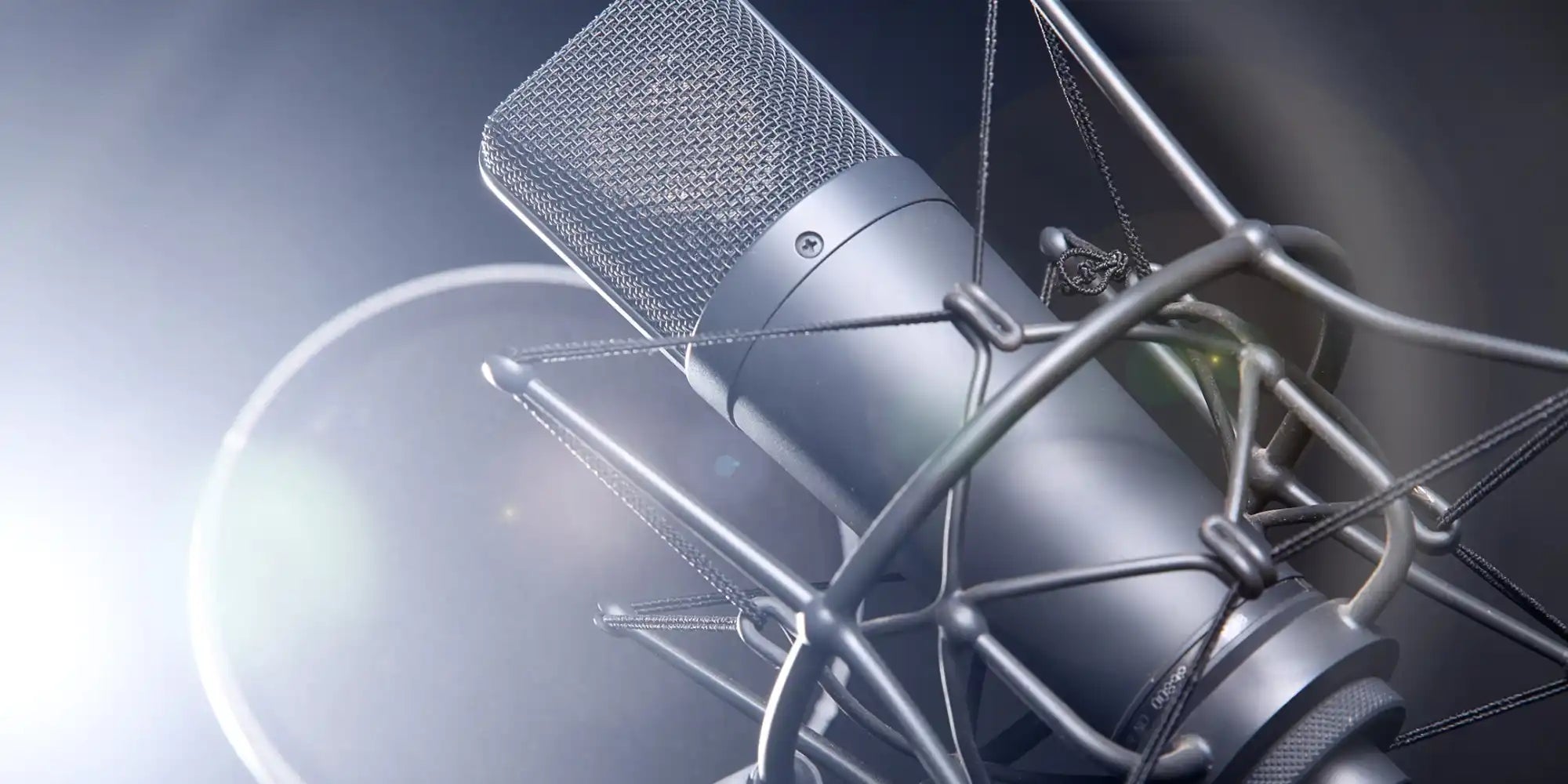 Silver condenser microphone with shock mount and pop filter, likely a neumann u87 model.