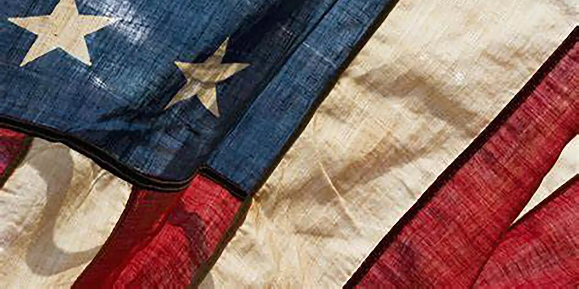 Vintage american flag with blue stars and red stripes on a white background, made of fabric.