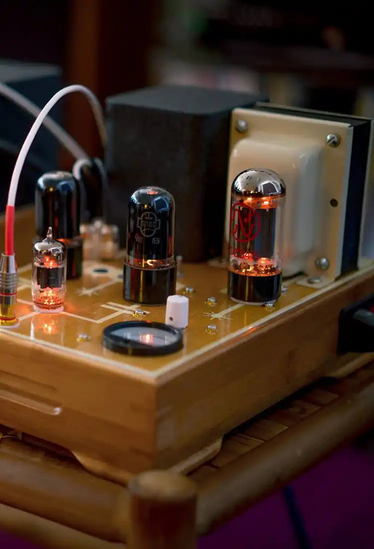 Vintage-style wooden audio amplifier with glowing red tubes and black components.